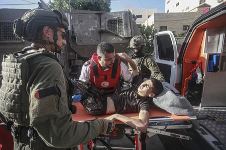 Palestinian paramedics carry an injured Palestinian child into an ambulance after the Israeli forces shot him, following an Israeli military raid on the Palestinian town of Qabatiya, near the city of Jenin, in the northern West Bank. 4 Palestinians were killed and dozens injured, following an Israeli military raid. Israeli forces surrounded a school and destroyed streets and infrastructure.