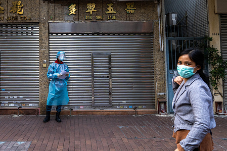 A woman wearing a facemask as protective measure against the COvid-19 coronavirus walks in front of a health worker dressed in PPE (Personal protective equipment) at a mobile Covid-19 testing site.
Multiple mobile testing vans are in operation in Hong Kong to provide residents free of charge Covid-19 testing services as the Covid-19 coronavirus continues to spread in the city.