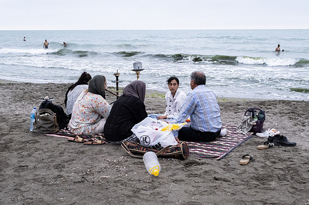 A family seen sitting at the beach while smoking a hookah. Amid an unprecedented summer heatwave in Iran, many residents are seeking refuge in coastal cities like Chalus to escape the extreme heat and humidity affecting much of the country. In contrast to the sweltering conditions elsewhere, northern regions offer cooler weather, drawing large crowds to the Caspian Sea coast. Chalus and nearby areas have become key destinations, known for their milder climate and beaches, offering relief from the oppressive summer conditions.
