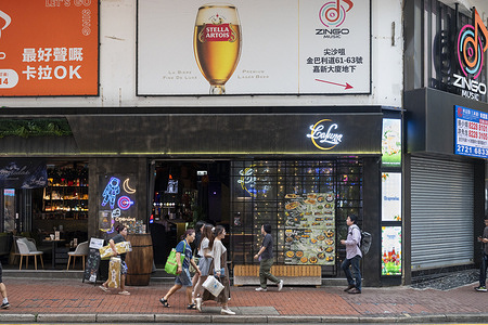 Pedestrians walk past a street commercial advertisement from the Belgian pilsner beer brand, Stella Artois, in Hong Kong.