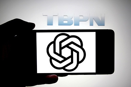 In this photo illustration, an Open AI logo is seen displayed on a smartphone with a TBPN logo in the background.