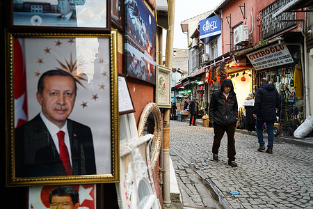 People walk through a market as a portrait of Turkish President Recep Tayyip Erdogan hangs at a shop in Istanbul.