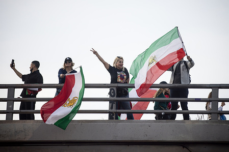 Protesters wave Iranian flags and flash peace signs from a 101 Freeway overpass in Los Angeles during the Global Day of Action — Iran Solidarity Rally.