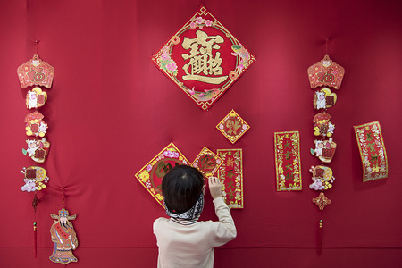 A child helps his mother to decorate with Chinese New Year ornaments their textile shop.
The former british colony of Hong Kong is preparing for the Lunar Chinese New Year 2018. People in the city are busy decorating to welcome the year of dog.