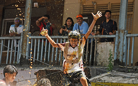 A Hindu devotee loses balance after breaking dahi handi (earthen pot filled with curd) during the Krishna Janmashtami festival in Mumbai. Krishna Janmashtami is celebrated as birth of lord Krishna by Hindu devotees by singing devotional songs and fasting for a day till the midnight. The next day Dahi Handi (pot filled with curd) is celebrated on streets by breaking a high hanging pot filled with curd as re-enactment of lord Krishna's childhood where he would often steal curd and butter from the pot kept at a height by his mother.