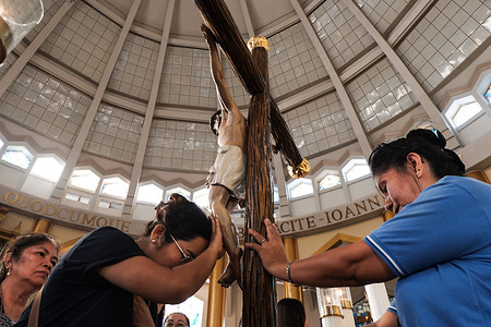 Catholic devotees touch a wooden crucifix during the Veneration of the Cross at a Good Friday service in Antipolo Cathedral. This central ritual of the Lord’s Passion invites the faithful to offer a physical act of gratitude—a kiss, a touch, or adoration—symbolizing a personal connection to the sacrifice of Jesus Christ. For many, the gesture is a profound expression of faith in the promise of salvation, marking the somber climax of the Holy Week liturgy.