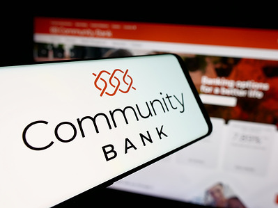 In this photo illustration, a smartphone with the logo of financial company Community Bank N.A. (CBNA) is seen on screen in front of website.