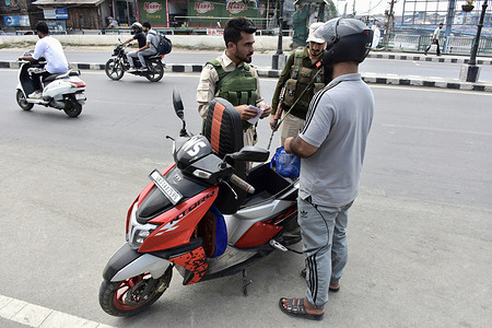 Policemen search a motorcyclist at a temporary check-post ahead of the India's 79th Independence day.