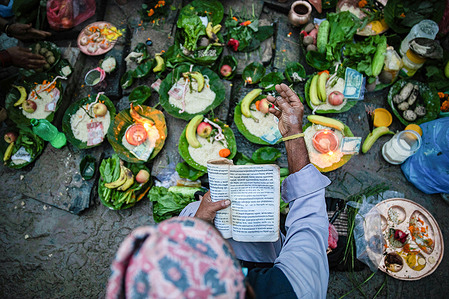 A Hindu priest recites prayers from a holy book while performing a ritual next to the bank of Bagmati River during the Kuse Aunse (Father's Day) celebration.
Hindus all over the country, whose fathers have passed away, come to the temple to worship, holy dips, and to present offerings on this occasion.
