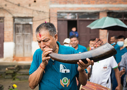 A man plays a traditional instrument made of an animal horn during the festival.
People celebrate Gai Jatra or cow festival in the memory of departed souls in the past year for salvation and peace. It is believed that cows guide the departed souls to cross the river to get to heaven.
