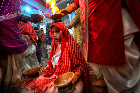 An Indian Hindu woman sits with burning fire pots on her hands and head as part of their ritual practice which includes blind faith and superstition to overcome every difficulties in coming future during the Maha ashtami celebration on the 8th day of Durga puja. Durga puja is the biggest Hindu festival running for 9 days all over India.
