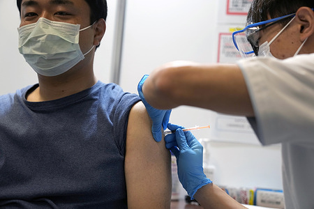 A local resident receives the booster shoot of the Moderna coronavirus vaccine at a mass vaccination center operated by Japanese Self-Defense Force Monday, Jan. 31, 2022, in Tokyo.