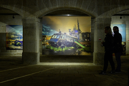 Visitors are seen walking by a picture with Police Riot Van by Banksy during Banksy´s Dismaland and Others exhibition at Alfandega Congress Center. The exhibition, includes images taken by Barry Cawston from the project Dismaland (2015), the well-known theme park created by Banksy, integrate other works identifying the artist as "Walled Off Hotel" (2017) or "Flower Thrower" (2005), one of his best known works. Apart of Barry images, the exhibition also integrates a series of works by young Portuguese artists, also serving as a launching pad for new names in the universe of urban art.