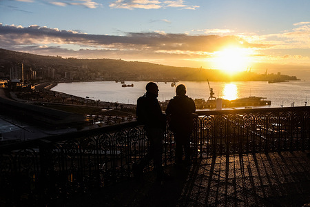 Two people seen watching the sunset in the city.