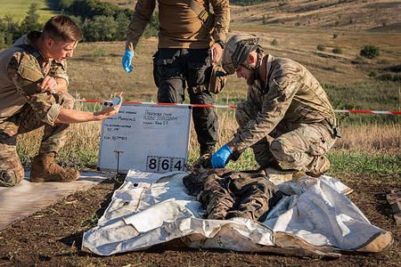 (EDITORS NOTE: Image depicts death)
Members of the NGO "Platzdam" carrying out identification tasks on the body of a Russian soldier. The Ukrainian NGO Platzdam has been working since the start of the full-scale invasion on the front lines, with the aim of recovering the bodies of soldiers , both Ukrainian and Russian, and returning them to their families.