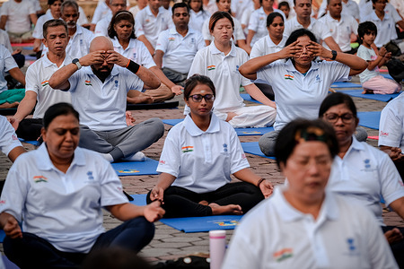 Participants are seen performing yoga exercises in conjunction with the 11th International Day of Yoga celebration at the Batu Caves Hindu Temple compound.