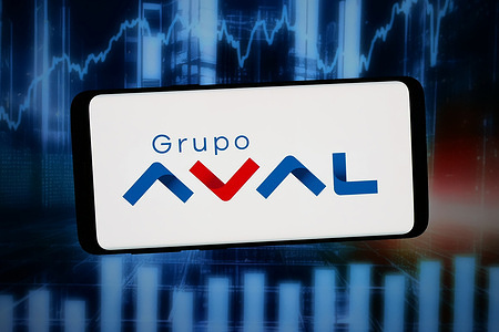 In this photo illustration, the logo of company Grupo Aval Acciones y Valores S.A. is displayed on a smartphone in front of abstract background on computer screen.