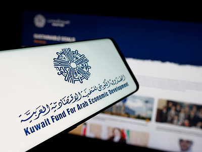 In this photo illustration, a smartphone with the logo of Kuwaiti arab economic development fund KFAED is seen on screen in front of website.