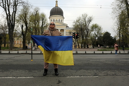 A participant holds a flag during the ‘Stop And Honor The Memory’ campaign on Preobrazhenska Street. Activists held a memorial event for the fallen defenders of Ukraine on Preobrazhenska Street. Every day at 9 am during a nationwide minute of silence, the memories of all fallen defenders of Ukraine are honored.