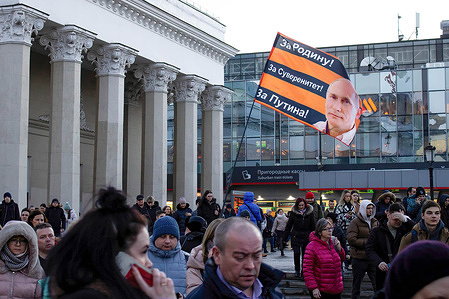 A supporter of Russiaís President Vladimir Putin waves a flag at the Komsomolskaya Square. The flag has a portrait of Putin on it. The text on the flag says: 'For Motherland! For sovereignty! For Putin!'.