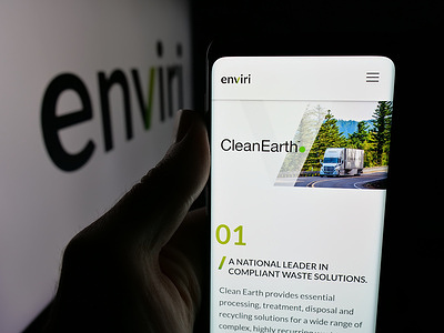 In this photo illustration, a person is holding a smartphone with the web page of US environmental company Enviri Corporation on screen in front of logo.