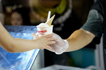 An ice cream vendor serves a person an ice cream, as Beijing is experiencing high temperatures.