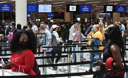 Travelers wait in line at a Transportation Security Administration (TSA) screening checkpoint at Orlando International Airport on the Friday before Memorial Day. As more and more people have received the COVID-19 vaccine, American Automobile Association (AAA) is predicting more than 37 million Americans will travel more than 50 miles this Memorial Day weekend, many for the first time since the pandemic began.