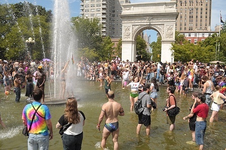 People stand in the water fountain at Washington Square Park near the New York City Pride March. The annual march celebrating LGBTQ+ culture, draws revelers, dancers and politicians to Manhattan, New York City. The march commemorates the 1969 Stonewall uprising in Greenwich Village, Manhattan where protesters demonstrated against a police raid on a gay bar called the Stonewall Inn.