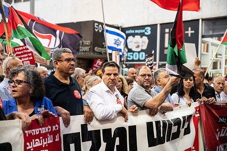 Hadash Israeli political party members walk in the joint Jewish and Arab Israeli rally against the Israeli occupation in the West Bank and Gaza, marking the occupation's 56th year.