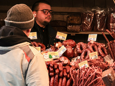 Visitors stop at a meat stall during the Christmas Market, one of the largest such markets in Europe with Christmas lights, fresh food, hot wine and gifts on the landmark Main Square.