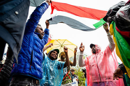 A group of Sudanese people dance below a Sudanese flag during the march.
From September 6th to 11th, an international Sudanese march took place starting in London and ending in The Hague after stopping in France and Belgium. On September 11th, the march arrived in front of the International Criminal Court building, situated in The Hague. The march was held in solidarity with the Sudanese revolution and calls for the prosecution of military criminals in Sudan. The march was organized by the Sudanese Initiative Europe.
