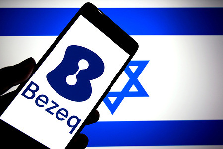 In this photo illustration, a Bezeq logo is seen displayed on a smartphone with the flag of Israel in the background.
