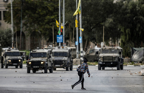 A Palestinian youth throws stones at the Israeli army vehicles, in the protest against the storming of Askar camp for Palestinian refugees near Nablus in the occupied West Bank. Israeli army stormed the Askar refugee camp and arrested a wanted Palestinian.