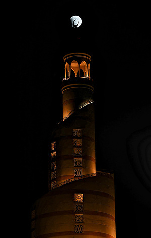 A "Blood Moon" appears during a total lunar eclipse above the spiral minaret of the Abdullah Bin Zaid Al Mahmoud Islamic Cultural Center.