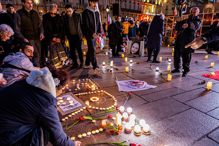 Participants kneel to light candles arranged on the ground forming a memorial display during the vigil. Supporters of the National Council of Resistance of Iran (NCRI) held a candlelight vigil at Place Saint-Michel to honor victims of Iran’s nationwide uprisings, calling for justice. Demonstrators chanted the slogans “No Shah, No Mullah” and “No to dictator” echoing calls inside Iran that reject all forms of dictatorship whether clerical rule or the former monarchy.