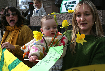 Mothers and children hold signs and a bunch of daffodils during the protest in Parliament Square in London .The protest organised by No Births Behind Bars is standing in solidarity with all mothers, parents and carers serving custodial sentences, separated from their children. In addition the group are calling for an end to the imprisonment of pregnant women.