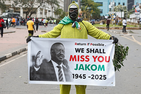 A mourner displays a banner outside the Kenyan Parliament building where the body of former Prime Minister Raila Odinga is expected to be kept for people to pay tribute. Kenyans gathered in the city to mourn the death of former Kenyan Prime Minister Raila Odinga. He passed away at the age of 80 while receiving medical treatment at a hospital in India.