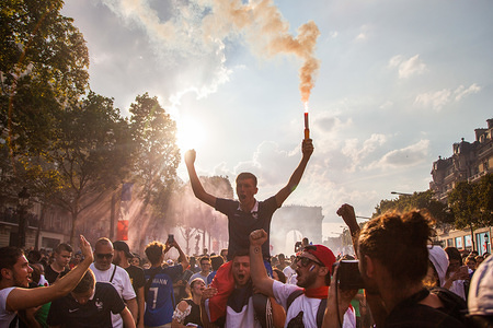 A man seen holding a flare as thousands of supporters gathers at Champs Elysées to receive the world champion French national soccer team. On Saturday 15 of August, France beated Croatia by the score of 4-2, becoming the champion of the world cup for the second time in history.