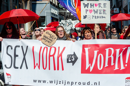 A group of sex workers and supporters are seen holding a banner during the demonstration.
After a social media campaign called 'I Am Priceless' to ban prostitution in The Netherlands. Proud Nederland the Dutch association by and for sex workers demonstrated against this petition, holding their characteristics red umbrellas and frames for reframing the profession. Proud believe that sex work should be seen as a fully-fledged profession. The petition hit 42,000 signatures this week, meaning it's passed the 40,000 mark needed to be debated by politicians. Prostitution has been legal in the country since 2000 but the petition, launched by Christian inspired protest group Exxposé will now be heard by Dutch parliament.