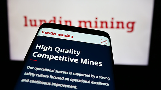 In this photo illustration, a mobile phone with the website of Canadian company Lundin Mining Corporation is seen in front of business logo.