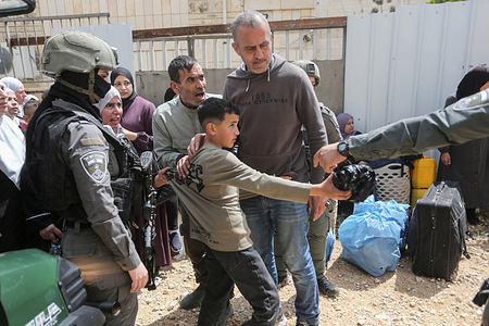 An Israeli soldier pulls a Palestinian child at an Israeli army checkpoint at the entrance to Jenin refugee camp, near the city of Jenin in the West Bank, to retrieve belongings from homes after the Israeli army forced them to leave the camp following a year-and-a-half-long military operation.