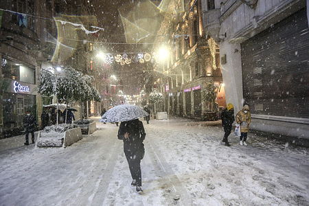 People are seen walking on Istiklal Street during the heavy snowfall.