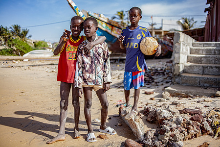 Three African children stand on an urban beach during the Christmas holidays.