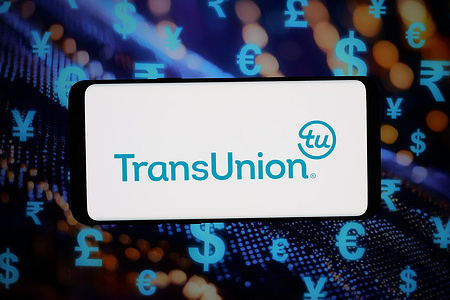 In this photo illustration, the logo of consumer credit reporting agency TransUnion is displayed on a smartphone in front of abstract background on computer screen.