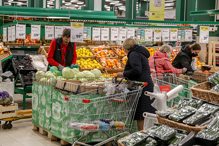 Shoppers with a cart choose vegetables and fruits at the Okey supermarket in St. Petersburg.
