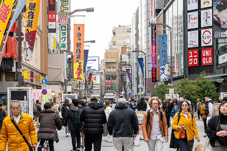 Pedestrians walk along a busy shopping street in Asakusa, Tokyo, Japan, near the Sensō-ji temple area. The district blends traditional attractions with modern retail and everyday city life. The Asakusa shopping district centers around Nakamise Street, a busy walkway lined with stalls selling traditional snacks, souvenirs, and crafts leading to Senso-ji Temple. The area blends a historic atmosphere with a lively retail scene, attracting both tourists and locals throughout the day.