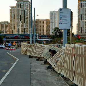 An elderly woman walks out from behind the roadworks fence at sunset.The abnormal heat is returning to the Moscow region, the daytime temperature from Thursday will exceed 30 degrees, according to the website of the Hydrometeorological Center of Russia.