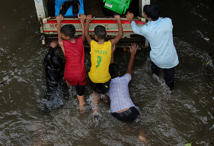 People pushing a vehicle stuck in a flooded road during the aftermath.
Heavy rainfall and strong wind disrupted normal life in the most populous city in India.