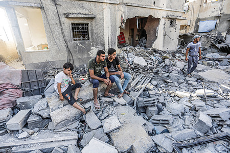 Palestinians sit among the rubble of a destroyed home belonging to the Shamlakh family after Israeli air strikes on southern Gaza City. Israel and Palestinian militants in Gaza confirmed the Egyptian-brokered ceasefire that came into effect on August 7, 2022, at 23:30 local time (20:30 GMT), three days after exchanging rocket attacks and airstrikes that killed one person.