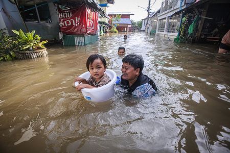 Villagers play with their children in flooded water in front of their house in Ayutthaya.